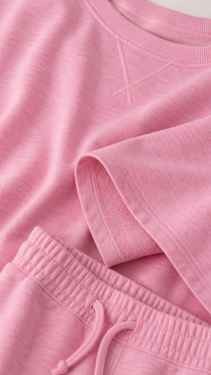 Close-up detail of pink sweatshirt collar and drawstring waistband showing knit texture