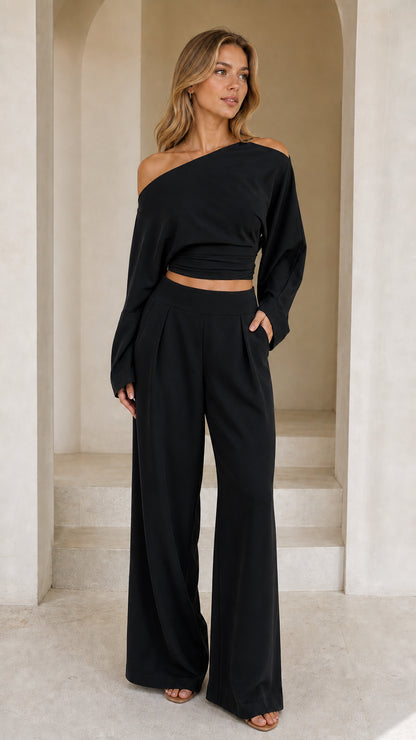 Full front view of model wearing black off-shoulder crop top and wide-leg pant set