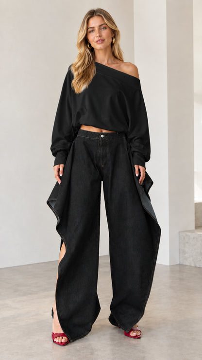 Full front view of all-black outfit featuring black draped wide-leg jeans and matching off-shoulder top
